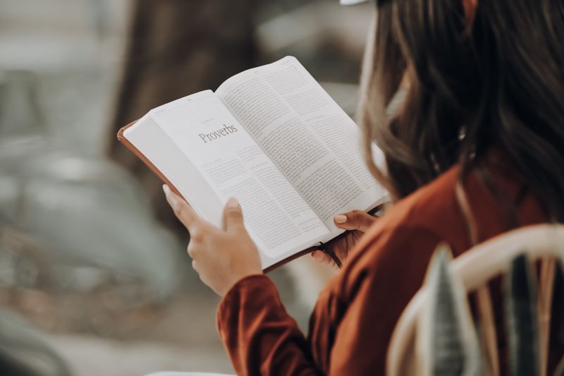 O femeie citește cartea Proverbele din Biblie.